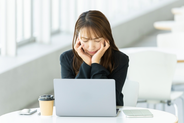 パソコンを前に悩む女性の画像